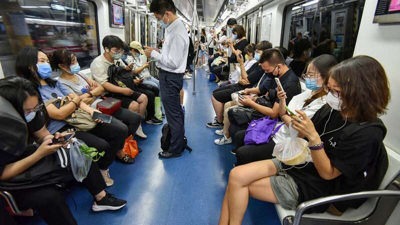 2022 年 7 月，人们在北京地铁上使用手机
